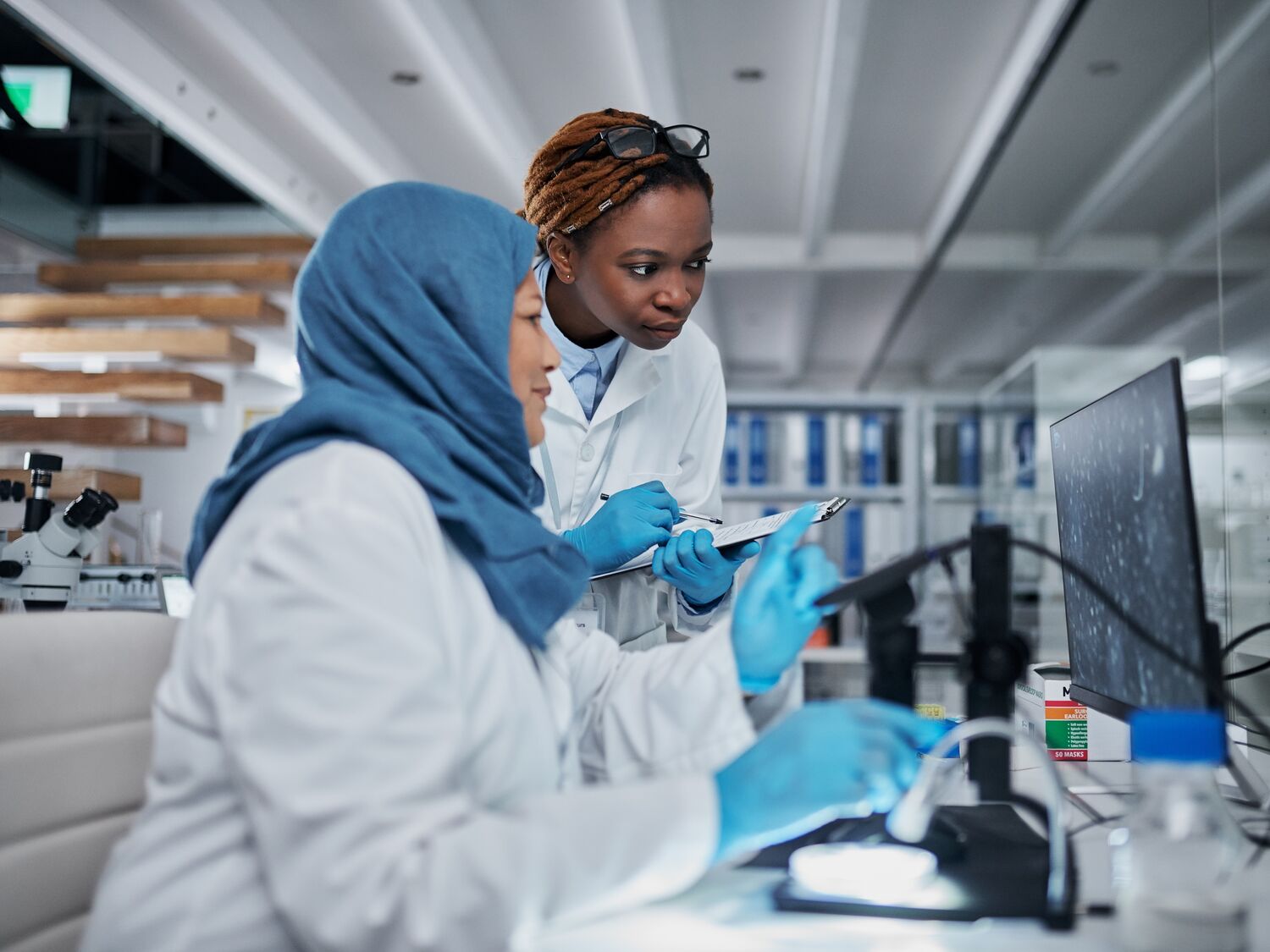 Two scientists in a lab and looking at the computer together.