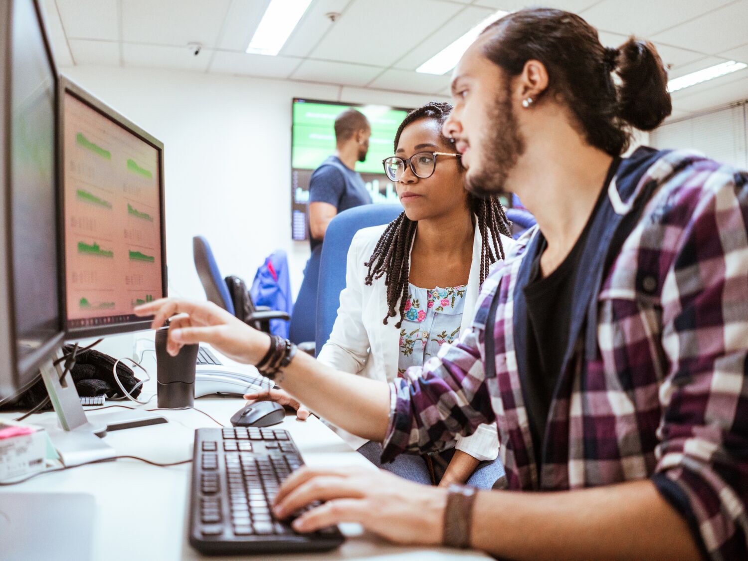 Business colleagues discussing with computer at desk in office