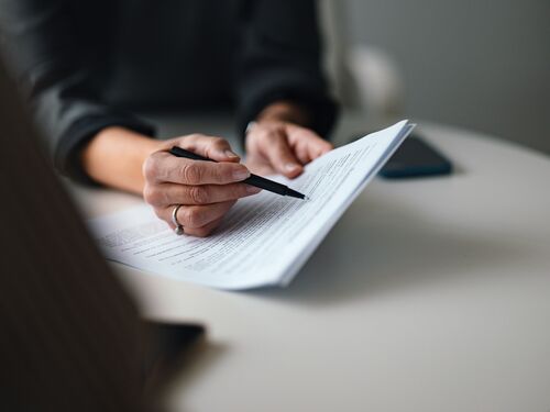 Close-up of a someone holding a pen and reviewing a document.