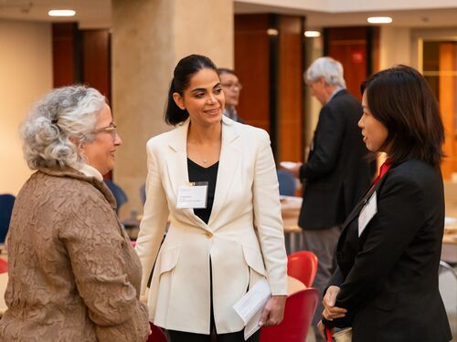 Kiana standing and engaging in a conversation at meeting.