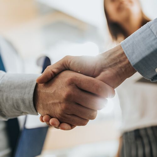 Close up of unrecognizable business colleagues shaking hands after reaching an agreement in the office.