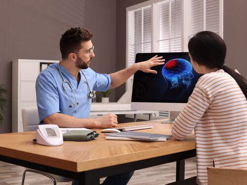 Neurologist showing brain scan to young woman in clinic