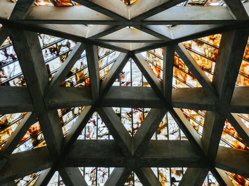 From below exterior of modern building with glass ceiling and metal beams in daylight