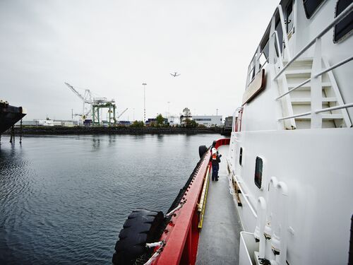 Two female naval architects wearing hardhats standing together on starboard side of tugboat during inspection