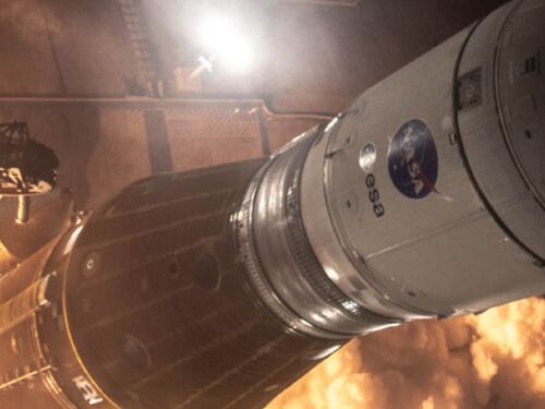 Close up of a space shuttle with a NASA logo lifting off from scaffolding, with ignition flames below.