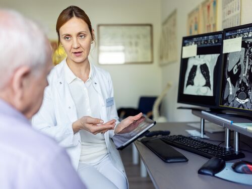 Doctors talking with senior male patient in CAT scan room. Surgeon discussing MRI scan results with senior man in hospital.