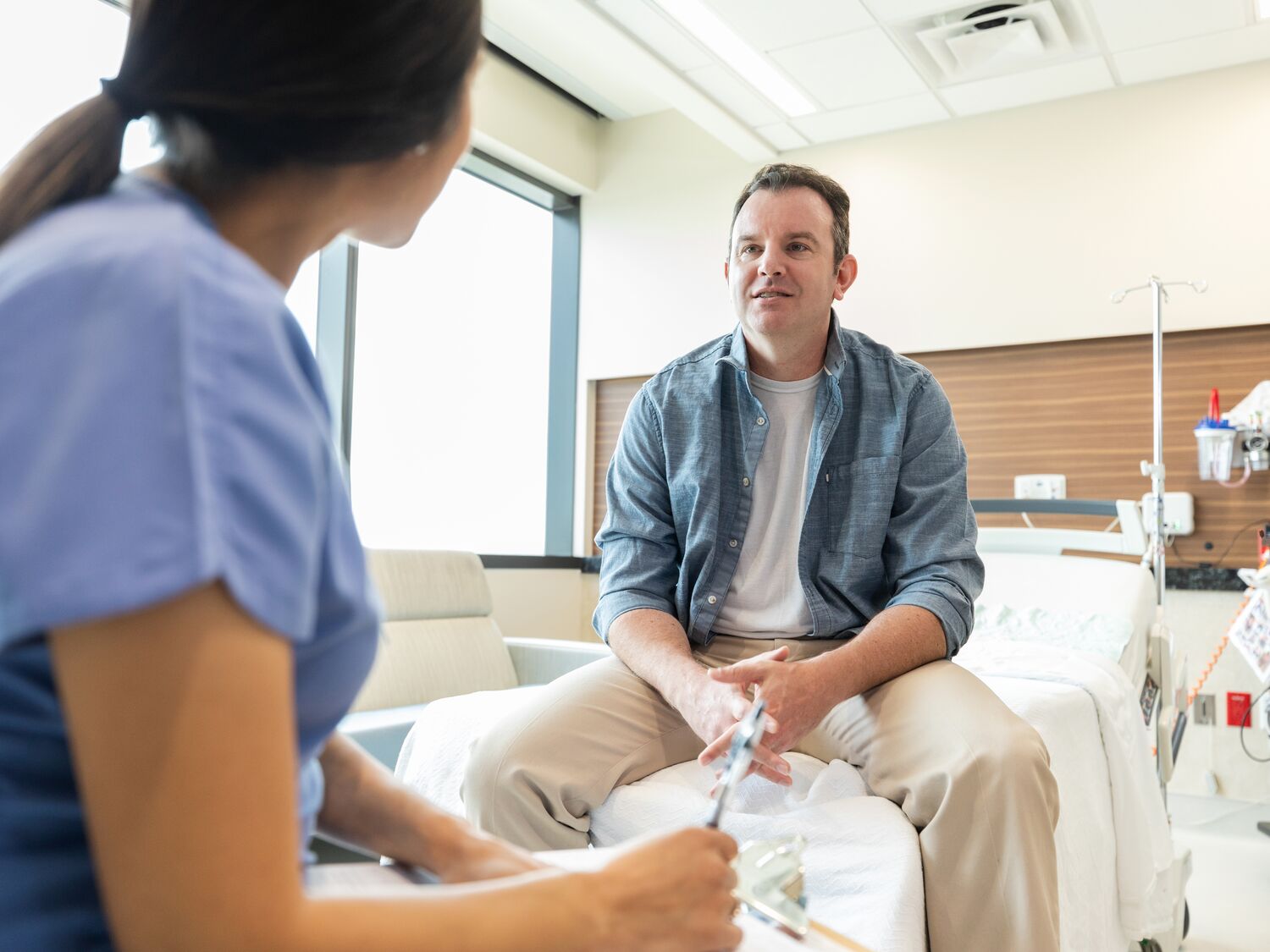 Male Patient Talking with Female Healthcare Worker in Hospital Room