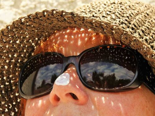 Woman wearing sunglasses and a hat looking up at the sky