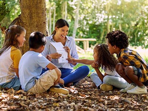 teacher doing a lesson with kids in a park