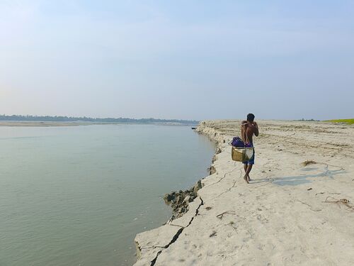 A man walking on sand next to water.