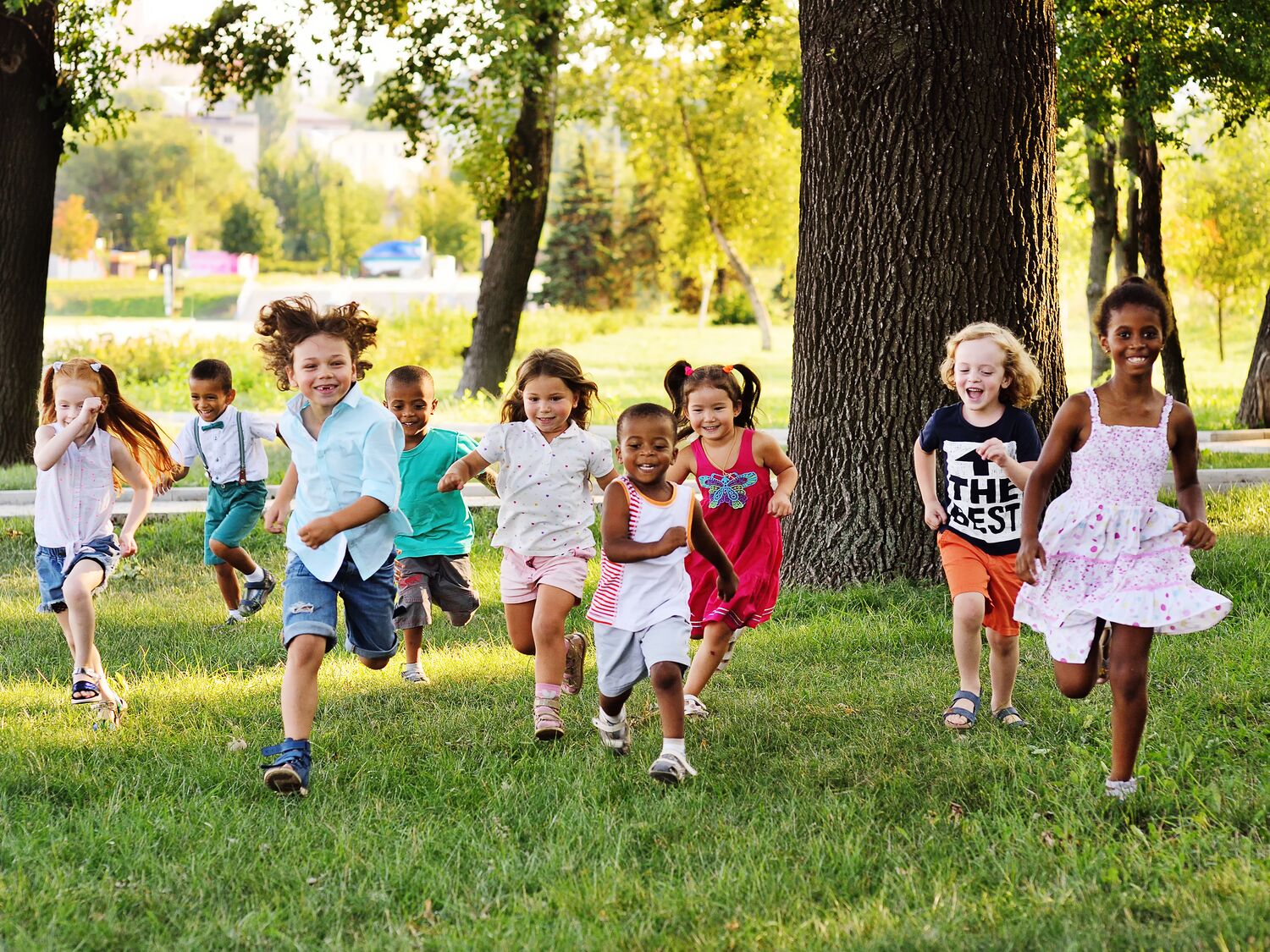 a group of preschoolers running on the grass in the Park
