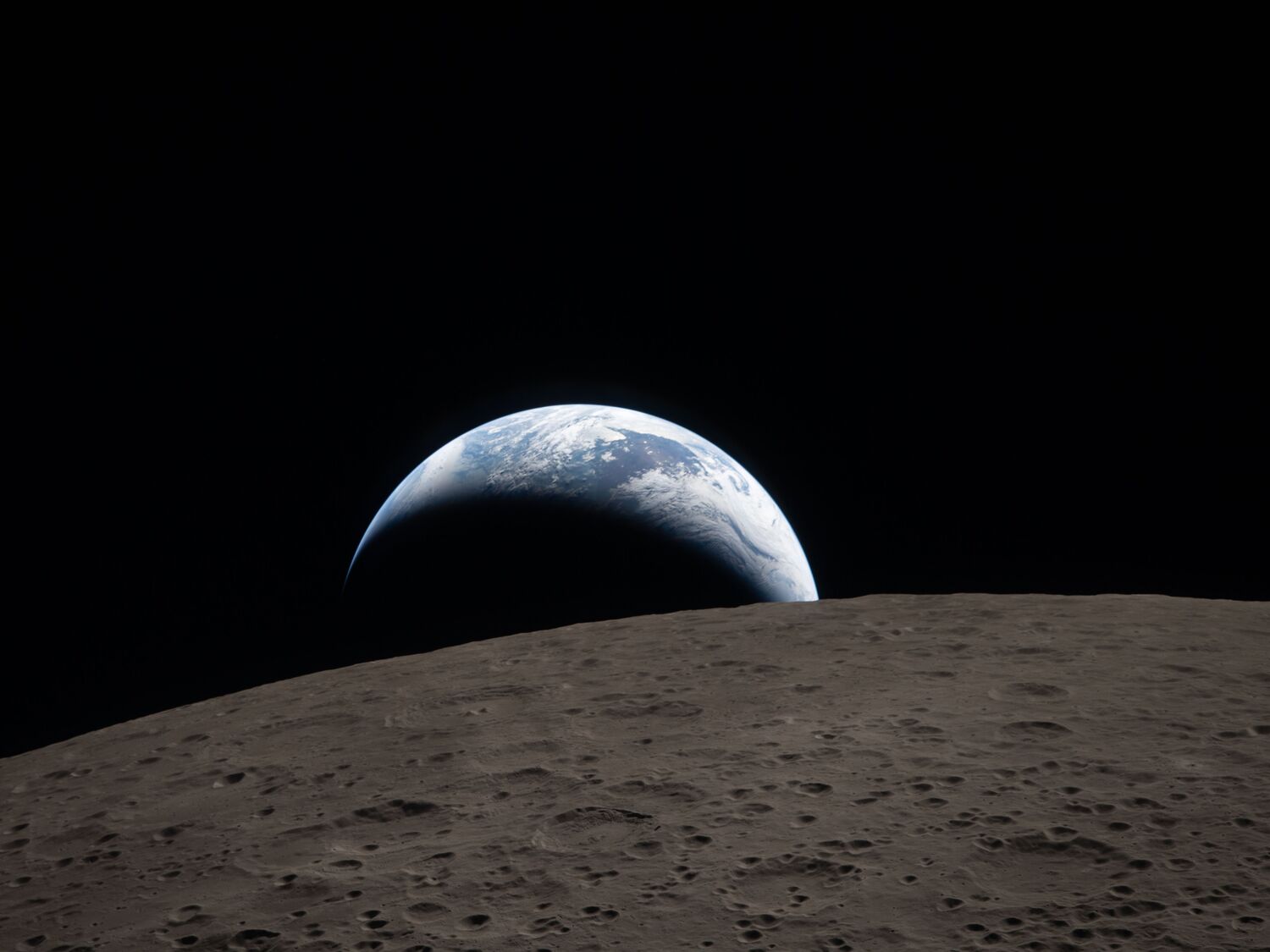art002e009288 (April 6, 2026) – Earthset captured through the Orion spacecraft window at 6:41 p.m. EDT, April 6, 2026, during the Artemis II crew’s flyby of the Moon. A muted blue Earth with bright white clouds sets behind the cratered lunar surface.
The dark portion of Earth is experiencing nighttime. On Earth’s day side, swirling clouds are visible over the Australia and Oceania region.  
In the foreground, Ohm crater has terraced edges and a flat floor interrupted by central peaks. Central peaks form in complex craters when the lunar surface, liquefied on impact, splashes upwards during the crater’s formation.