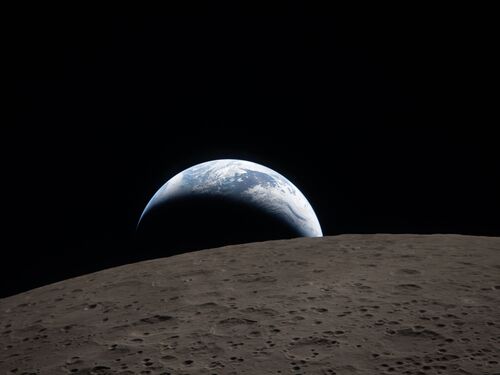 Earthset captured through the Orion spacecraft window at 6:41 p.m. EDT, April 6, 2026, during the Artemis II crew’s flyby of the Moon. A muted blue Earth with bright white clouds sets behind the cratered lunar surface.The dark portion of Earth is experiencing nighttime. On Earth’s day side, swirling clouds are visible over the Australia and Oceania region.  In the foreground, Ohm crater has terraced edges and a flat floor interrupted by central peaks. Central peaks form in complex craters when the lunar surface, liquefied on impact, splashes upwards during the crater’s formation.
