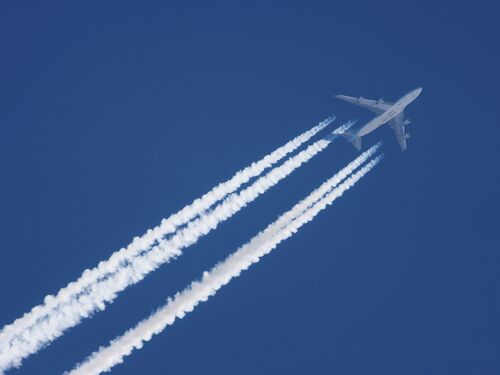 Airplane flying through a blue sky leaving contrails