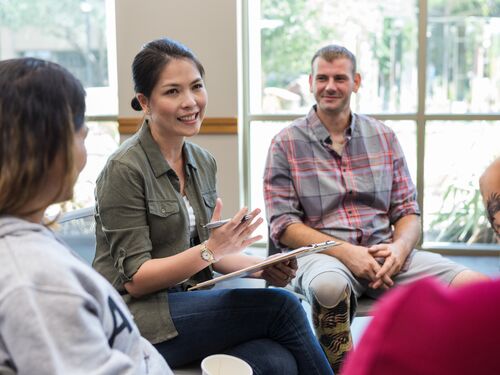 Participants engage in a group therapy session, sharing and listening to each other's stories.