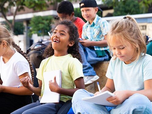 kids working on schoolwork while sitting outside