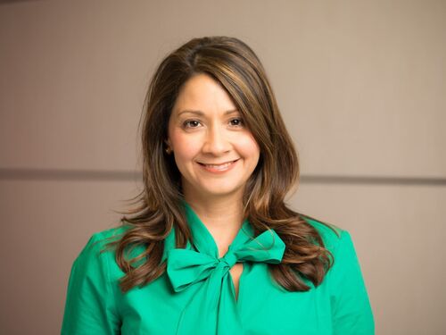 Frances Colon wearing a green blouse and smiling.