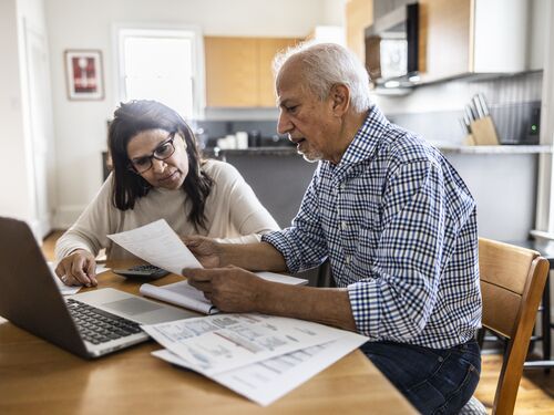Senior couple paying bills at kitchen table