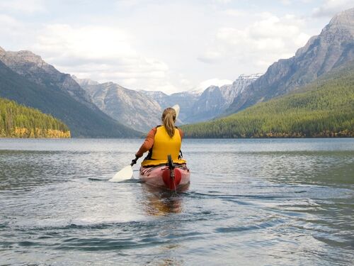 A young woman kayaking on a lake.