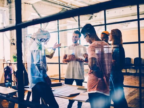 A group of co-workers standing and talking to each other at an office space.