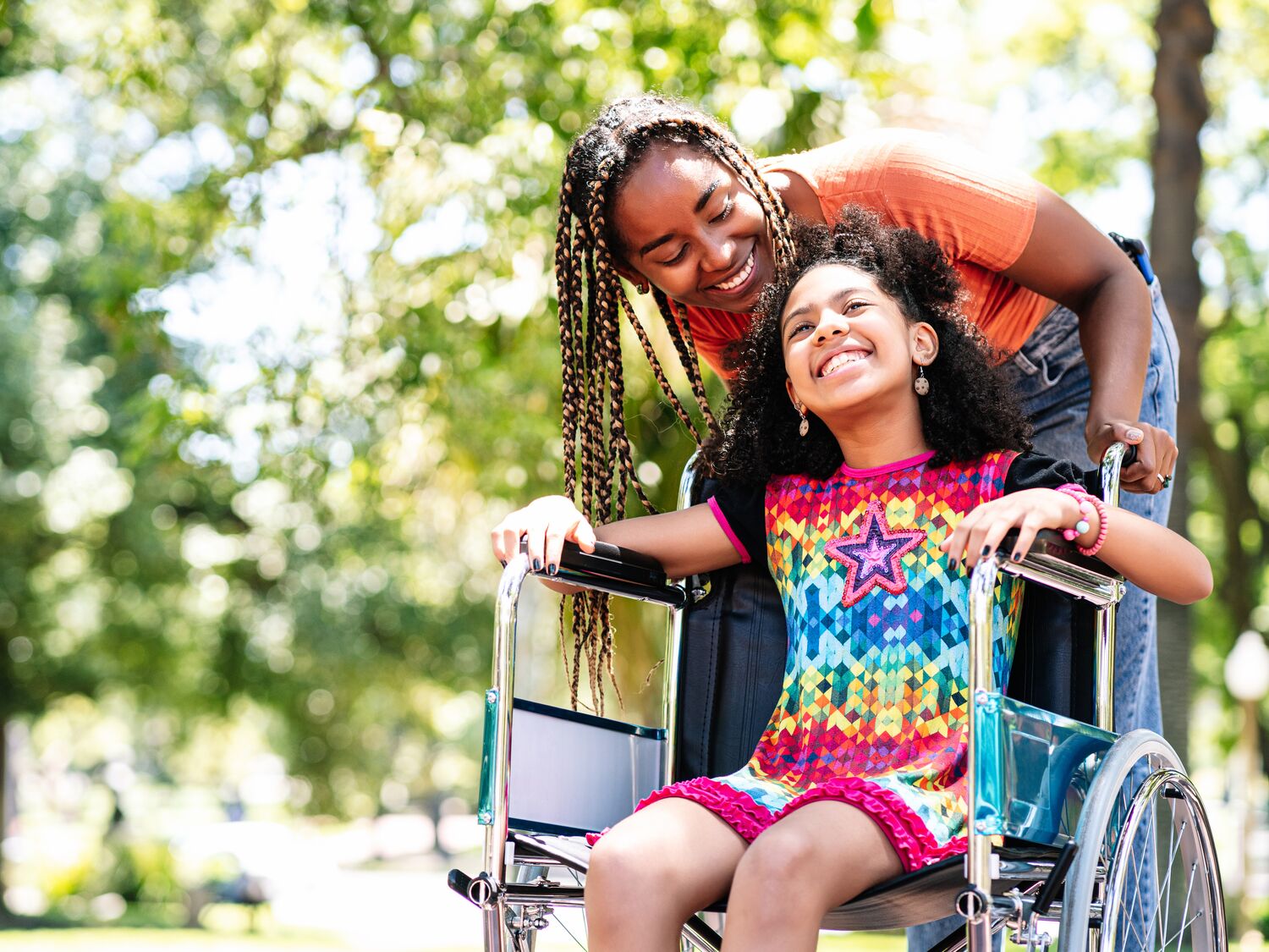 Little girl in a wheelchair at the park with her mother.