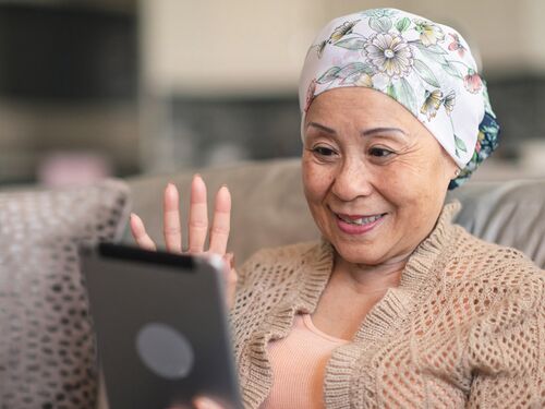 female cancer waving at someone on her tablet