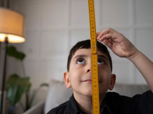 A young boy using a measuring tape.