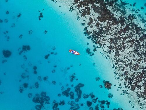 aerial shot of a boat next to a reef