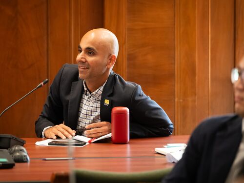 Mitul Luhar sitting at a table speaking into a microphone.