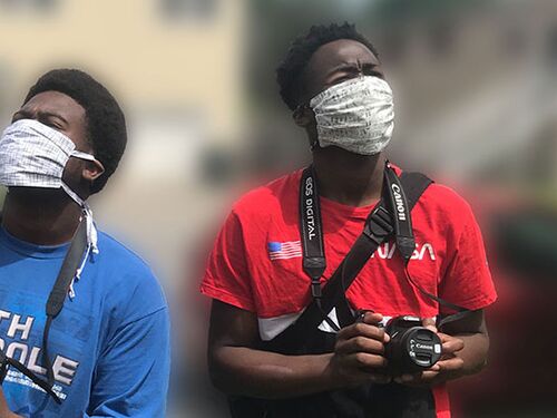 Youth Art Collective students Toby Agnew and Anthony Sonnier Jr., with cameras while wearing face masks.