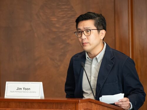 Jim Yoon wearing a suit and speaking to a long microphone.