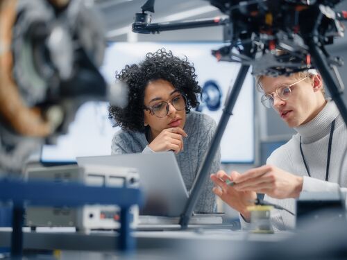 Diverse Engineers Discussing New Powerful Microchip to Put it Inside the Modern Drone. Innovative Technologies in Unmanned Aerial Vehicle Concept.
