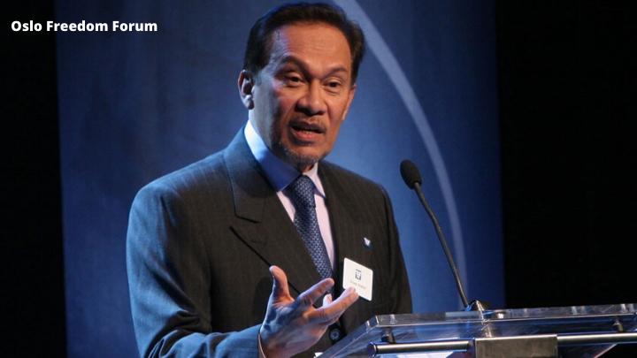 Anwar wearing a suit and speaking on a stand with a microphone.